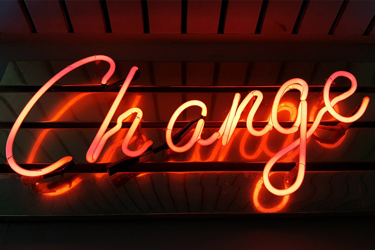 An orange neon light spelling the word "Change" on a dark background.